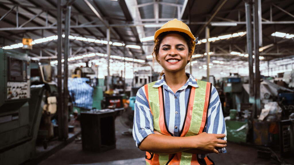 young woman smiling and working engineering in industry.Portrait of young female worker in the factory.Work at the Heavy Industry Manufacturing Facility concept.