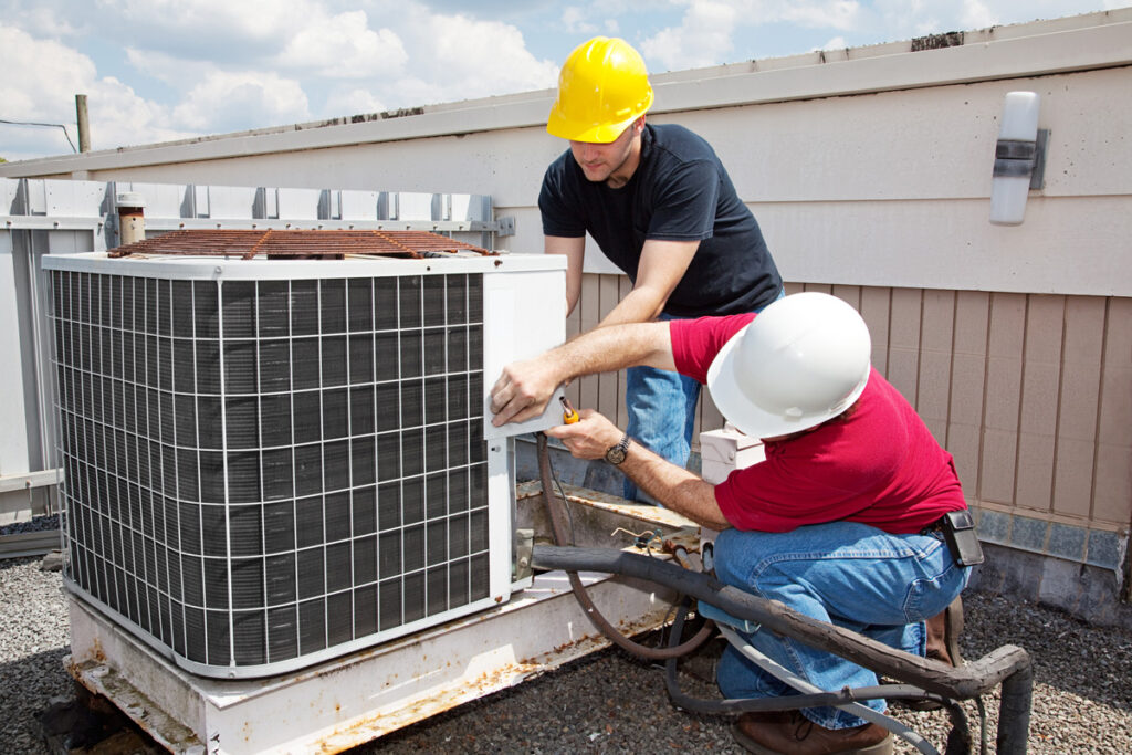 Two professionals working on an outdoor HVAC unit in Sunland Park.