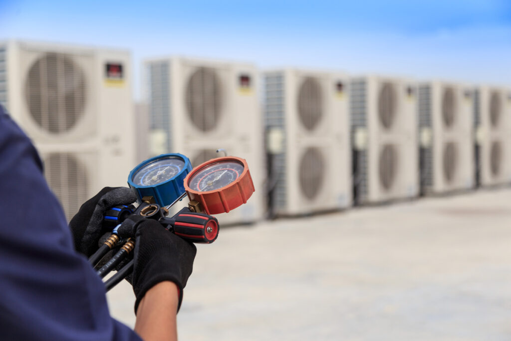 A person holding blue and red pressure gauges for a commercial HVAC system in Sunland Park.